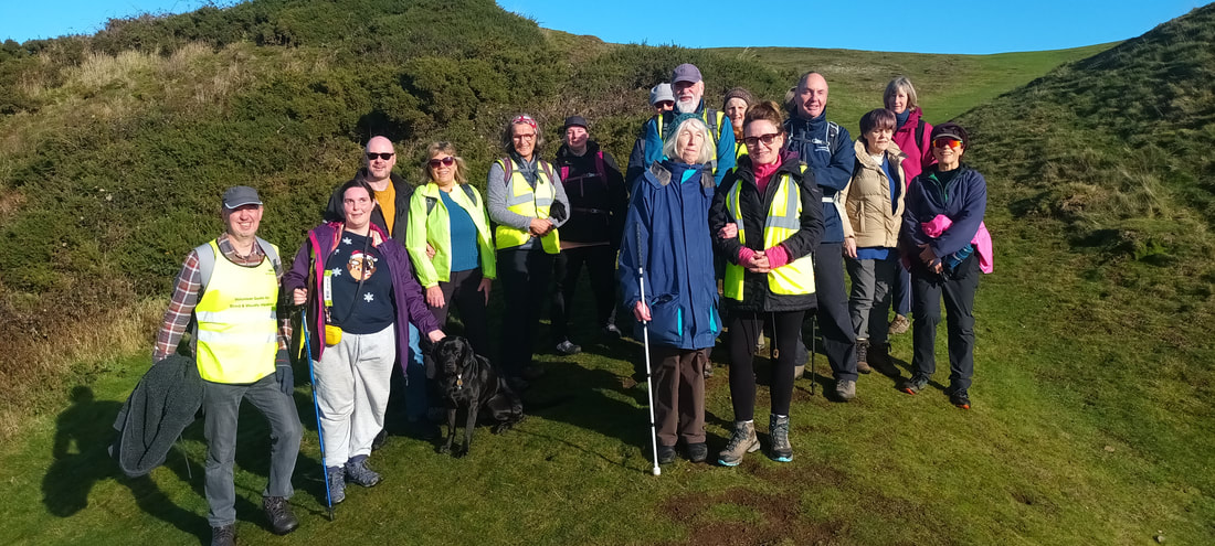 The group of walkers smile and pose for a photo on the hills.