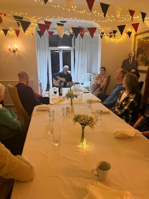 A man sings and plays guitar for the group in the evening at Copper Beech house.