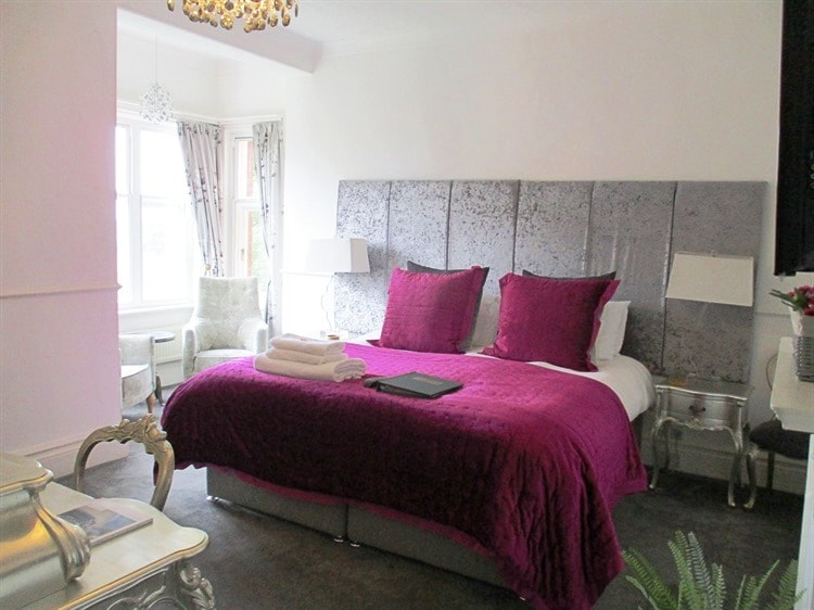 A comfortable double bedroom with purple bedspread.