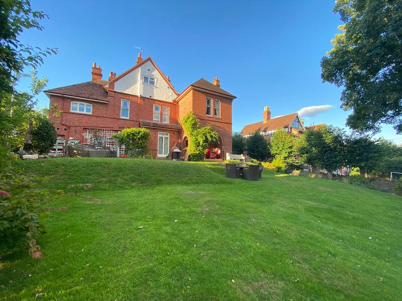 A view of the grand red-brick Copper Beech house from its garden.