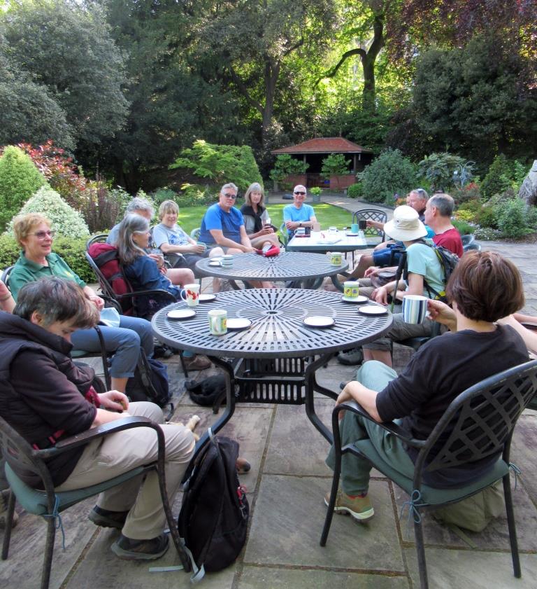A group of people seated at tables in a garden
