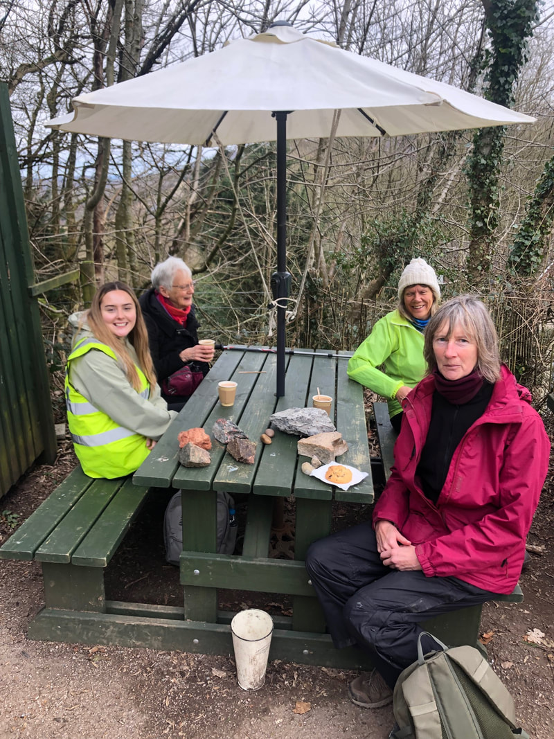 Walkers enjoy coffee and cake on a picnic bench.